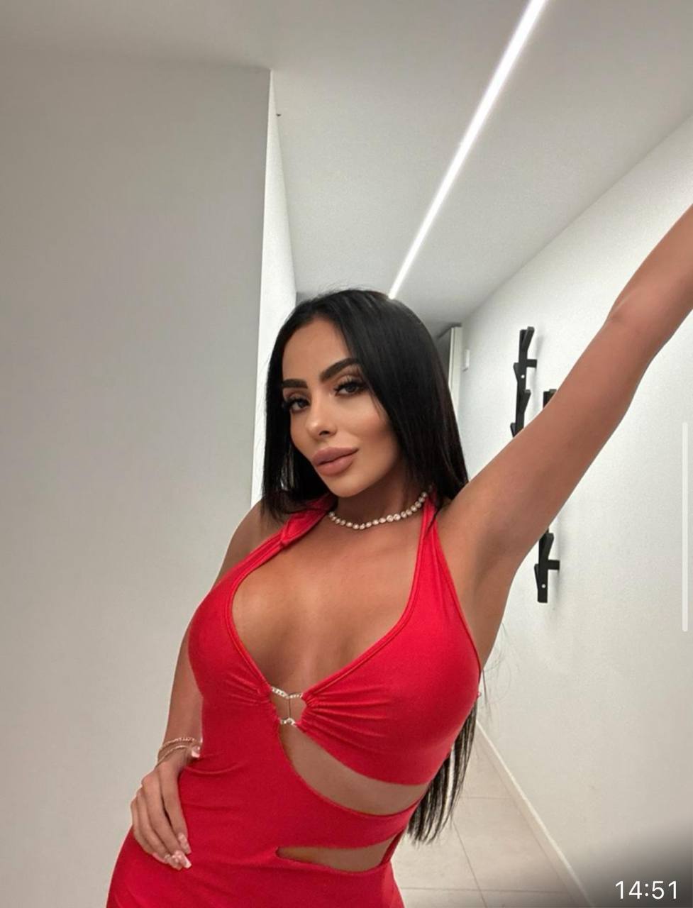 Selfie miroir en robe rouge dans un couloir moderne