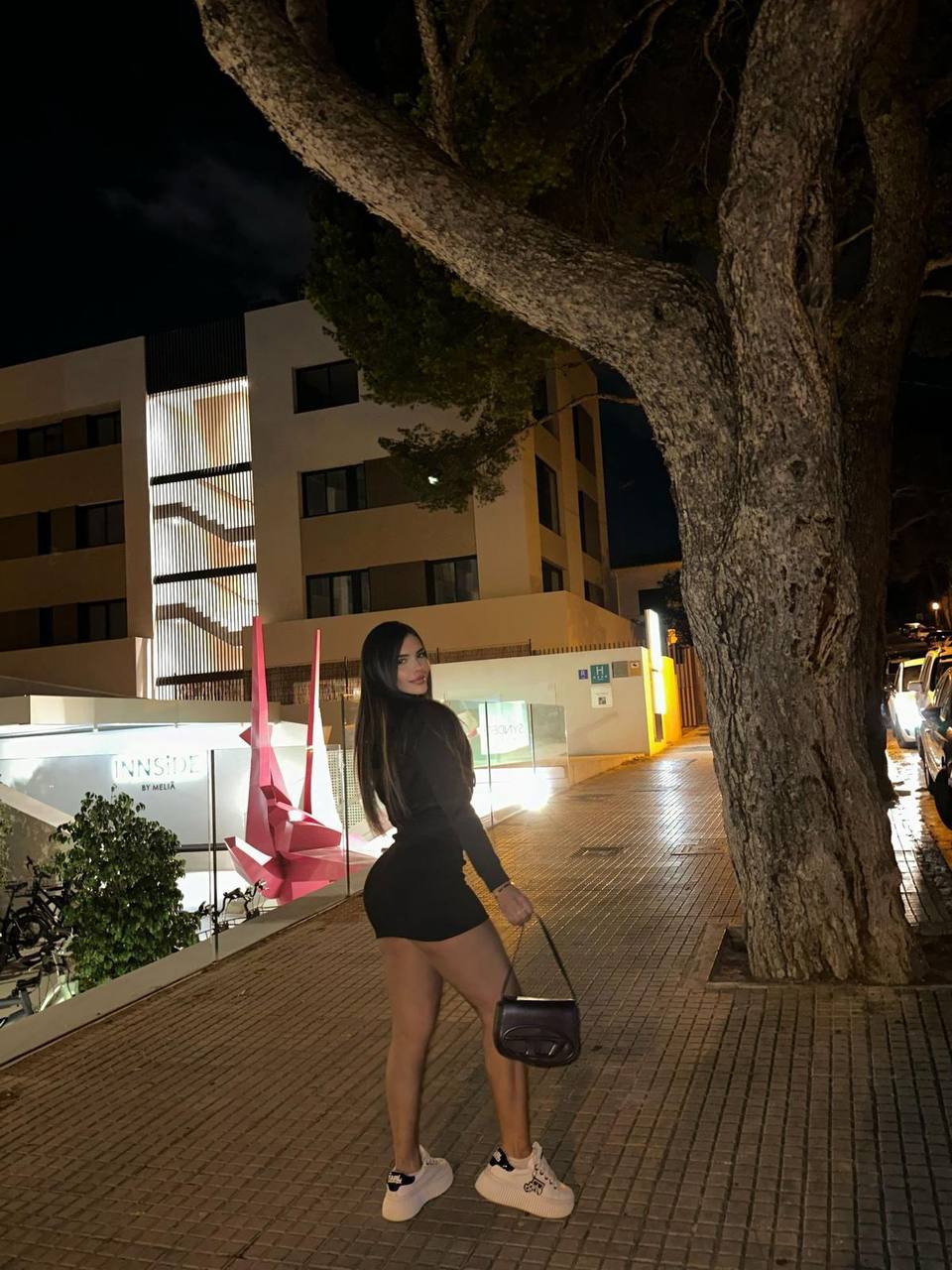Pose urbaine de nuit devant un hôtel illuminé